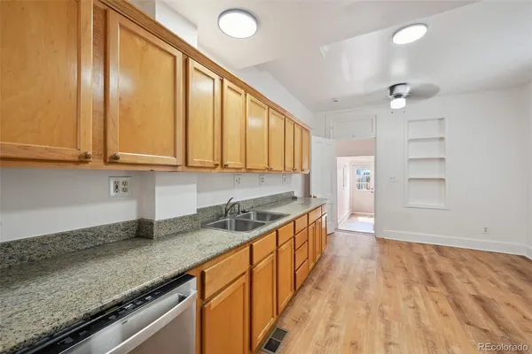 a kitchen with stainless steel appliances granite countertop a sink a stove cabinets and wooden floor