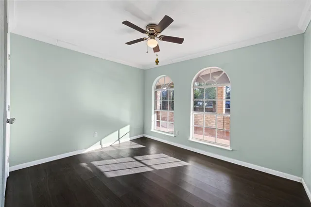 an empty room with wooden floor fan and windows