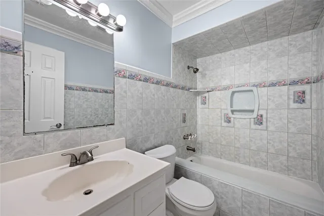 a bathroom with a bathtub shower sink vanity mirror and toilet