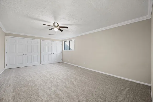 an empty room with chandelier fan and windows