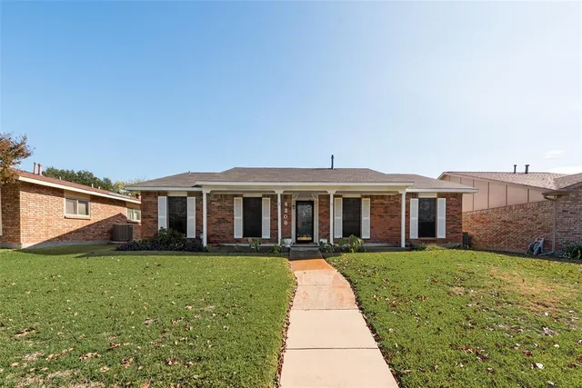a view of a house next to a big yard and large trees