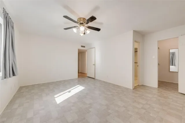 an empty room with closet and a chandelier fan