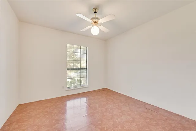 an empty room with windows and ceiling fan