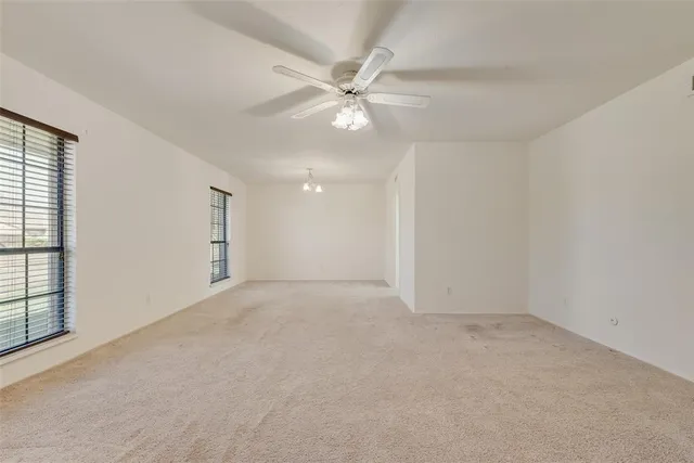 an empty room with a ceiling fan and a window