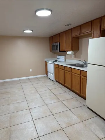a kitchen with granite countertop a sink a stove a refrigerator and cabinets