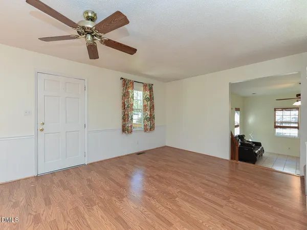 a view of empty room with wooden floor and fan