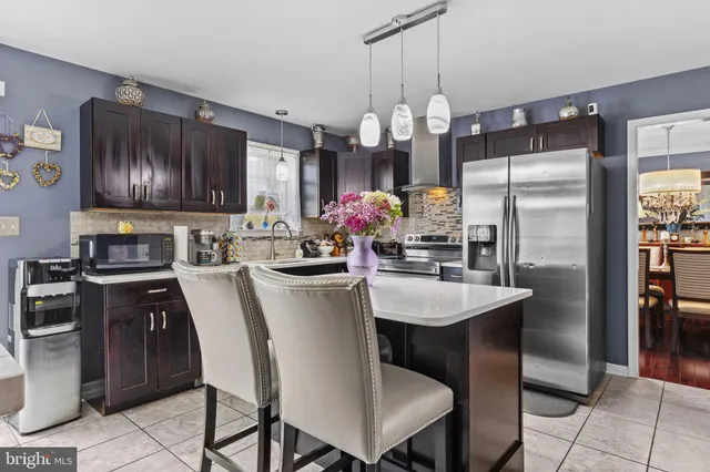 a kitchen with stainless steel appliances granite countertop a sink a stove a refrigerator cabinets and chairs