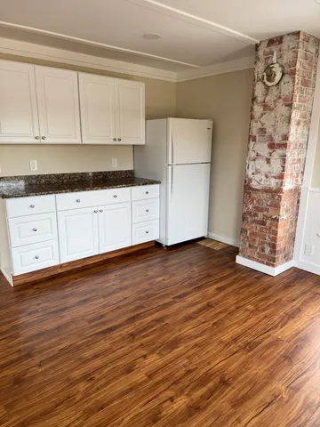 a kitchen with granite countertop white cabinets and wooden floor