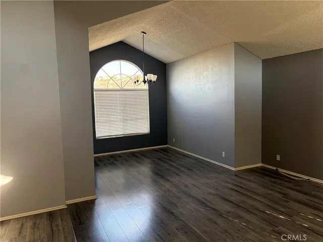 an empty room with wooden floor windows and entrance