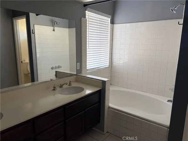a bathroom with a bathtub sink vanity and mirror