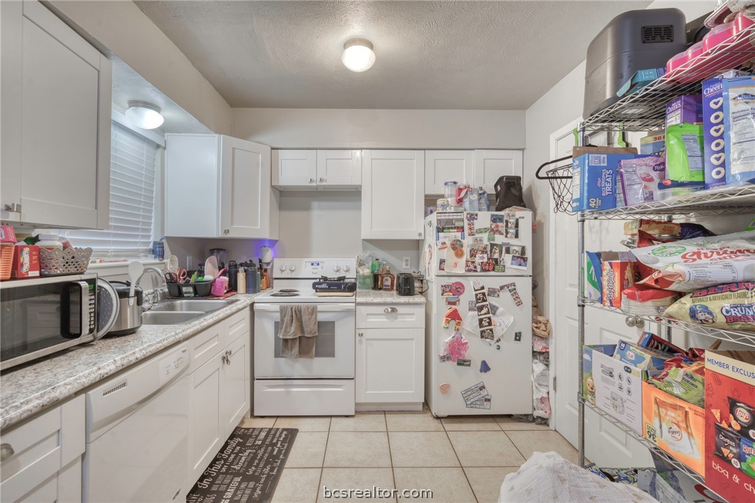1908 Barak Lane, Unit 14 Bryan, TX 77802 - Photo 6 of 10 Kitchen featuring white cabinetry, white appliances, sink, and light tile patterned floors