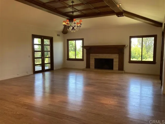 an empty room with wooden floor fireplace and windows