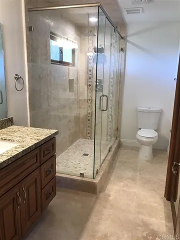 a bathroom with a granite countertop sink a toilet and shower