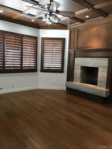 a view of an empty room with wooden floor and a ceiling fan