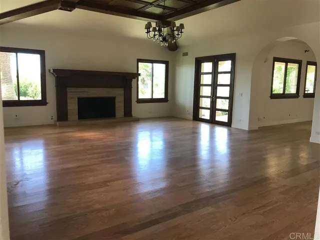 an empty room with wooden floor fireplace and windows