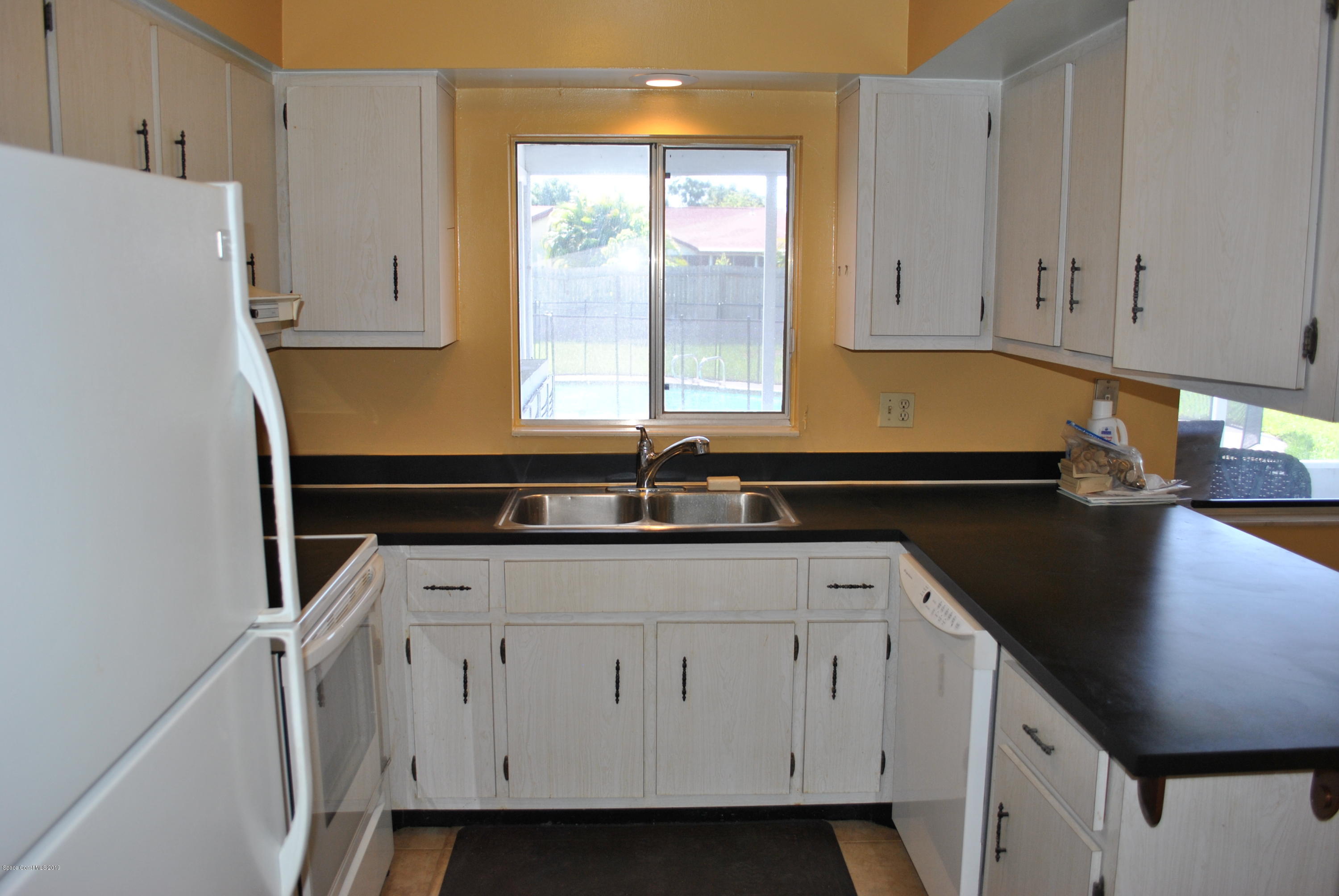 1167 Cotton Road Northeast Palm Bay, FL 32905 - Photo 3 of 34 a kitchen with white cabinets a sink a stove and a refrigerator