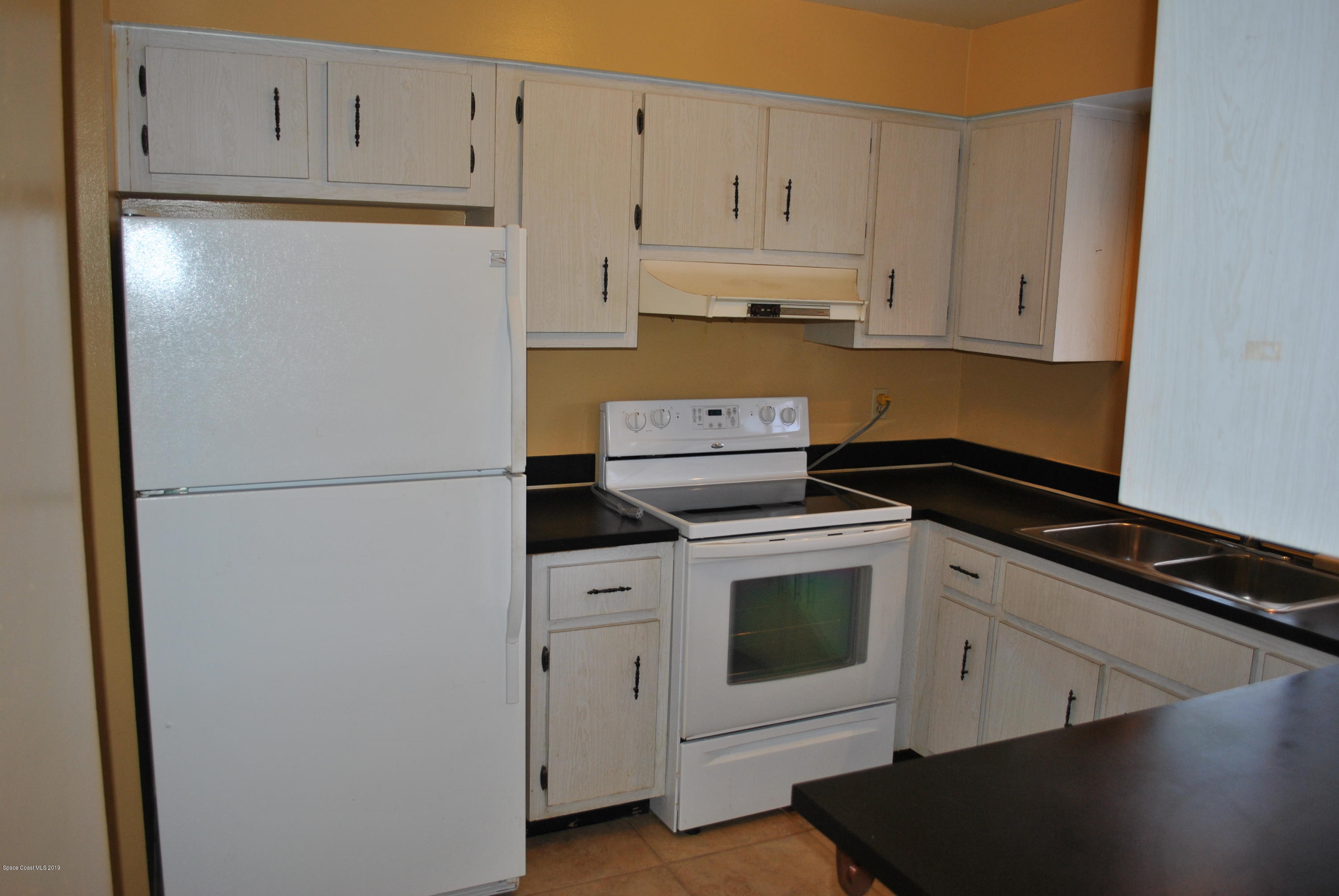 1167 Cotton Road Northeast Palm Bay, FL 32905 - Photo 4 of 34 a kitchen with white cabinets and white appliances