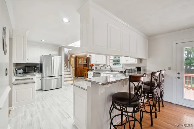 a kitchen with stainless steel appliances kitchen island granite countertop a table chairs refrigerator and a stove top oven