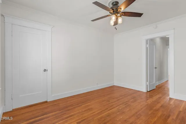 a view of an empty room with a window and wooden floor