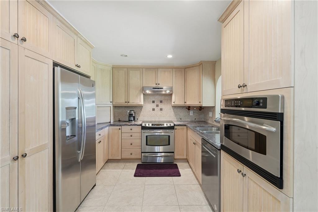 1316 Rordon Avenue Naples, FL 34103 - Photo 14 of 38 U-shaped kitchen featuring light wood cabinetry, stainless steel appliances, tile flooring, and a tiled backsplash