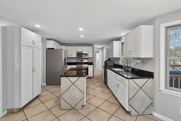 a kitchen with granite countertop a refrigerator and cabinets