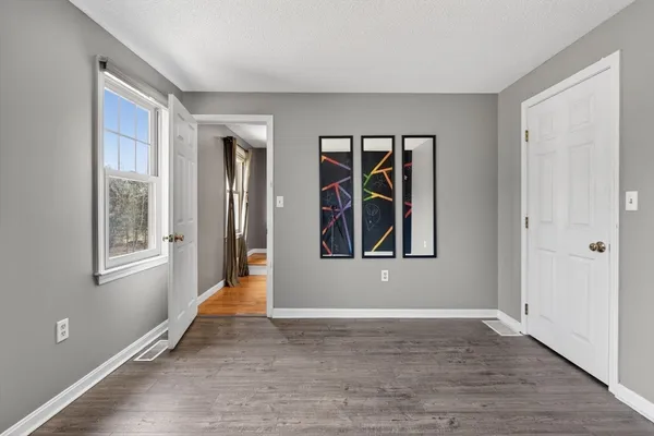 a view of an empty room with window and wooden floor