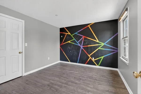 an empty room with wooden floor and ceiling fan