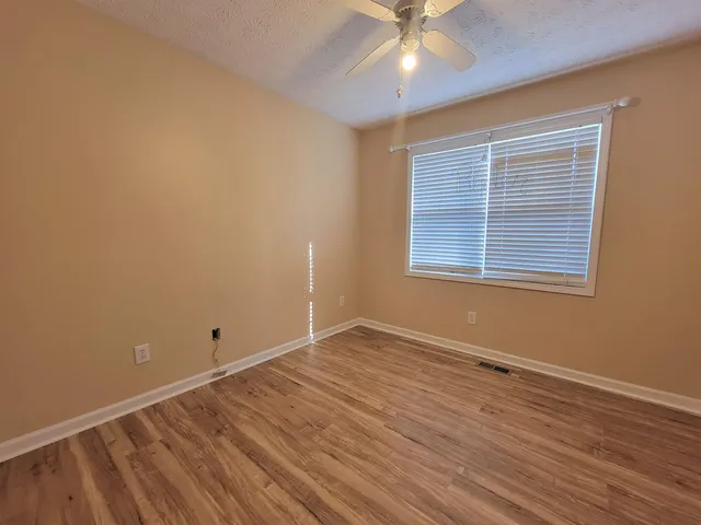 en empty room with wooden floor and windows