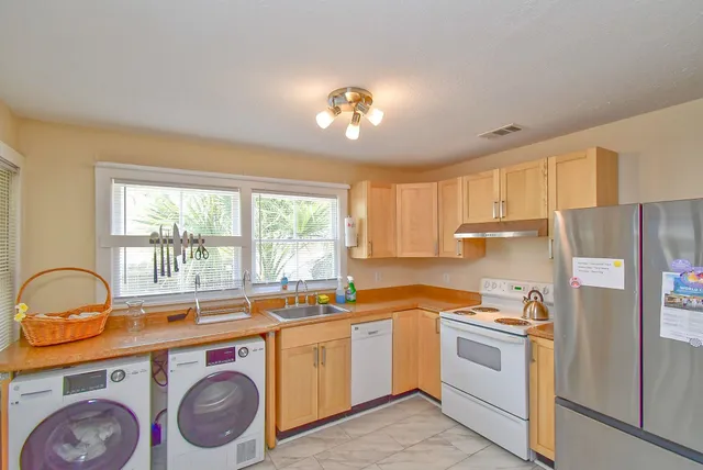 a view of a kitchen with a stove a sink cabinets and a window