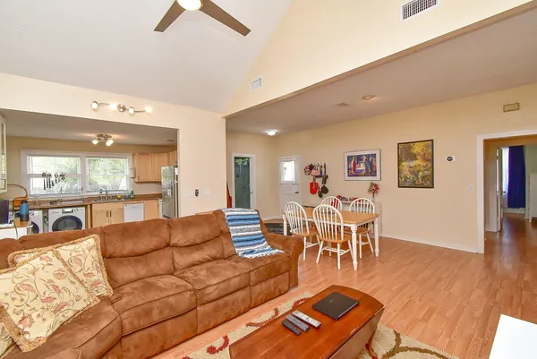 a living room with furniture and a dining table with wooden floor