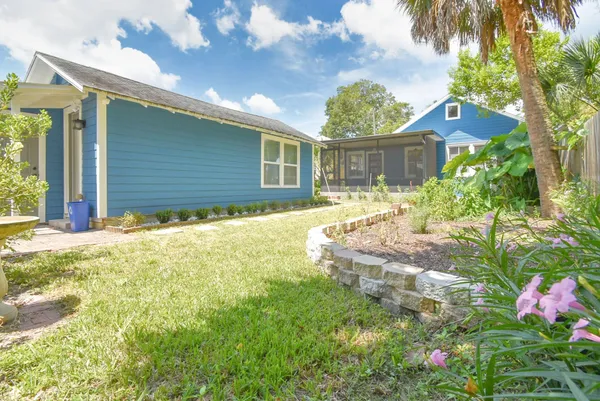 a view of a brick house next to a yard with potted plants