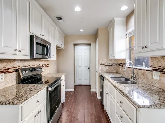 a kitchen with stainless steel appliances granite countertop a sink stove microwave and refrigerator