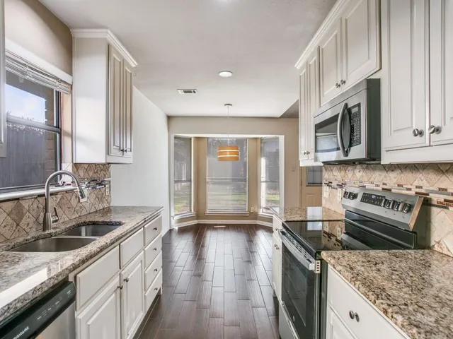 a kitchen with stainless steel appliances granite countertop a sink stove and cabinets