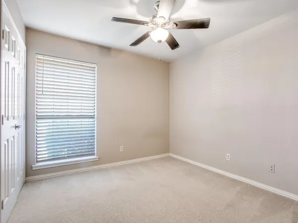 an empty room with a window and a fan