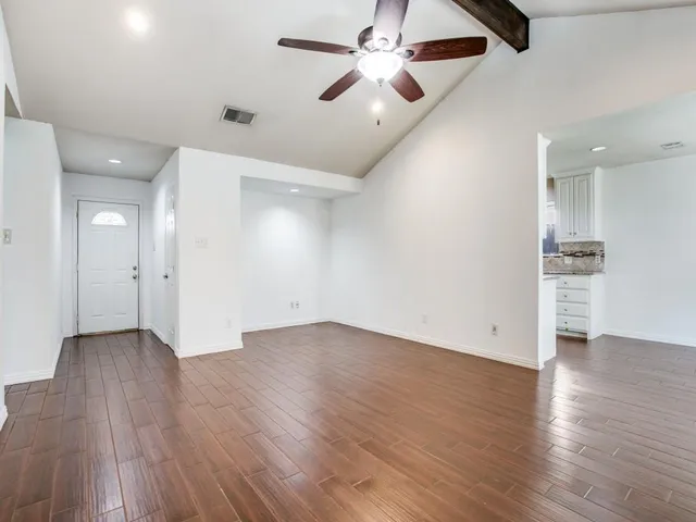 an empty room with wooden floor ceiling fan and windows