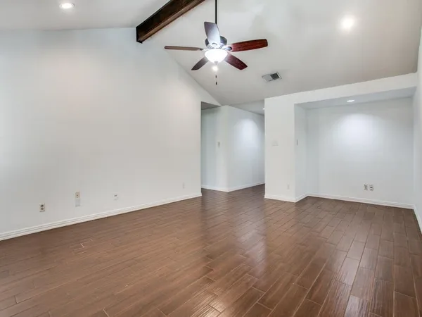 an empty room with wooden floor ceiling fan and windows