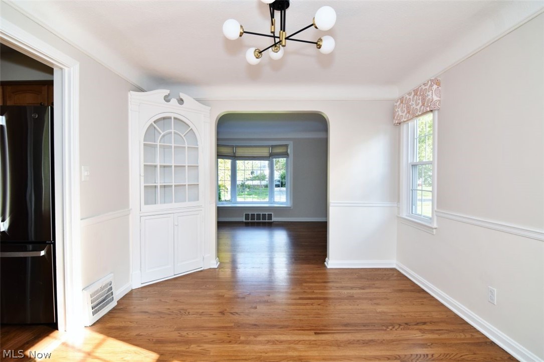5284 Edenhurst Road Lyndhurst, OH 44124 - Photo 11 of 50 Hardwood flooring, built-in corner display cabinet, architectural archway, contemporary chandelier, and bright windows