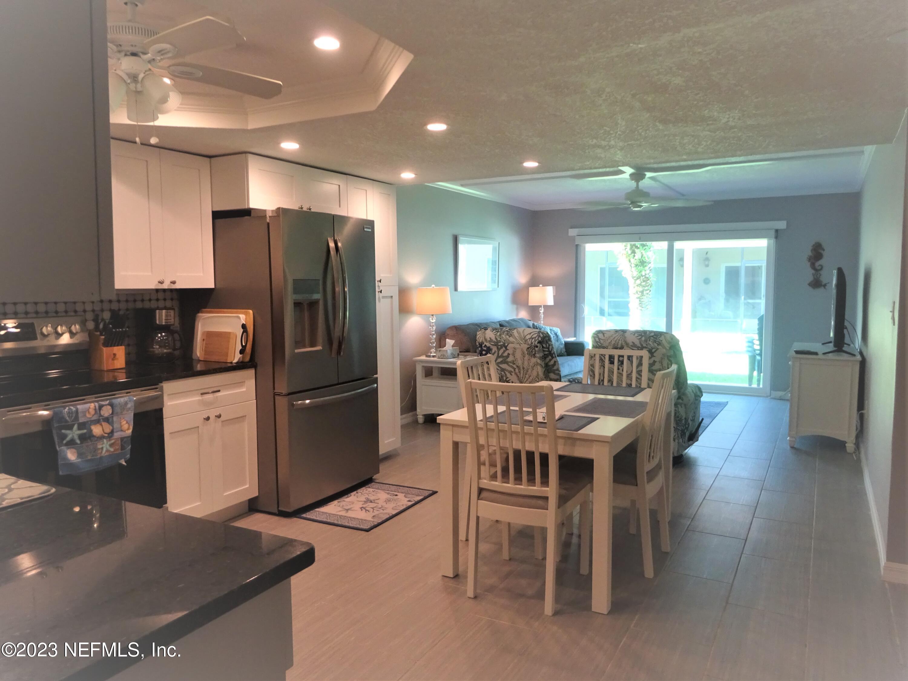 7175 A1A South, Unit F141 St. Augustine, FL 32080 - Photo 3 of 36 a kitchen with stainless steel appliances kitchen island granite countertop a refrigerator a stove a sink a dining table and chairs