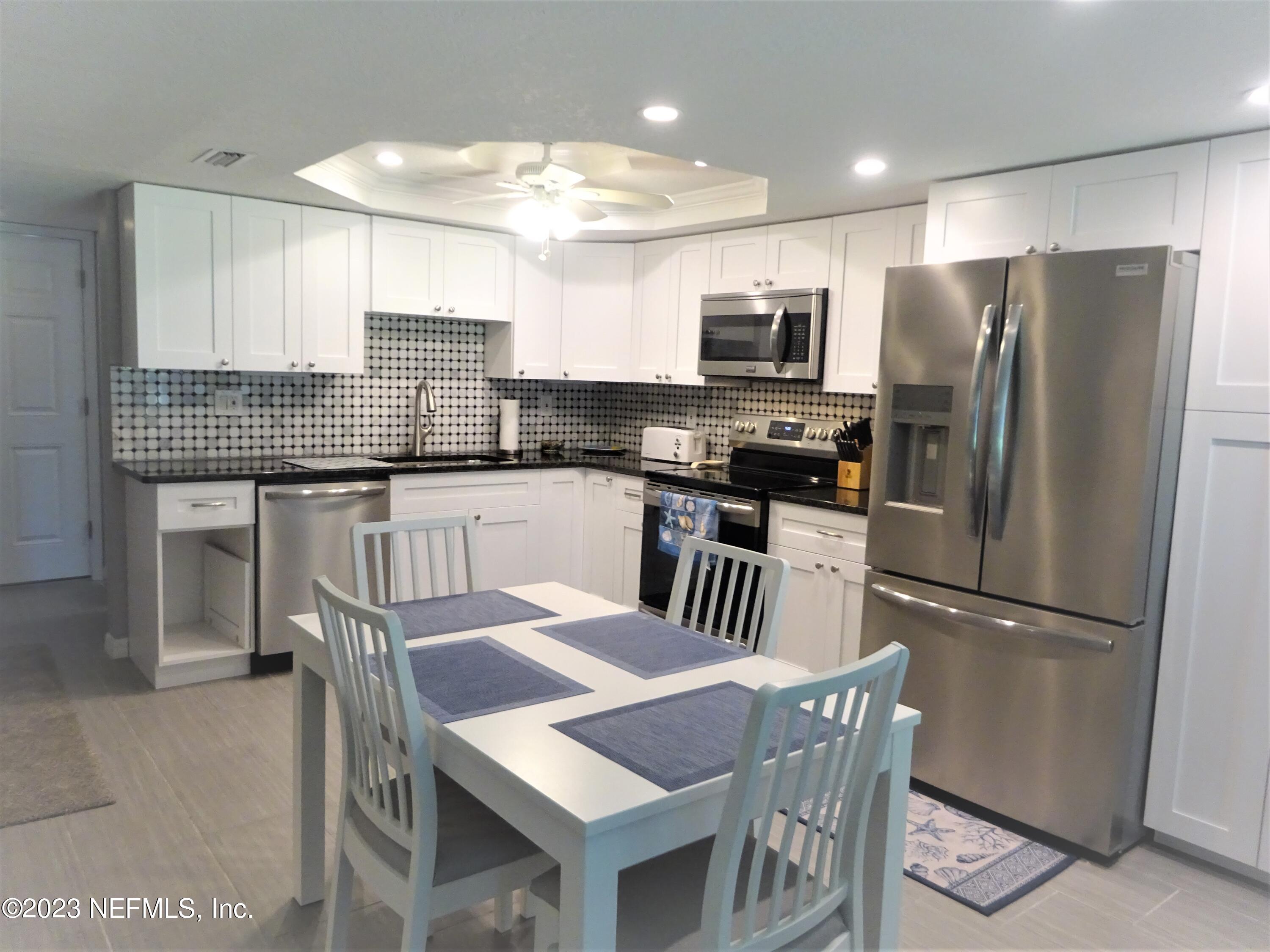 7175 A1A South, Unit F141 St. Augustine, FL 32080 - Photo 4 of 36 a kitchen with stainless steel appliances granite countertop a refrigerator a stove a sink a dining table and chairs