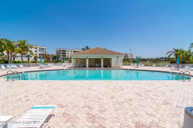 a view of swimming pool with a yard and palm trees