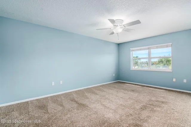 an empty room with windows and ceiling fan