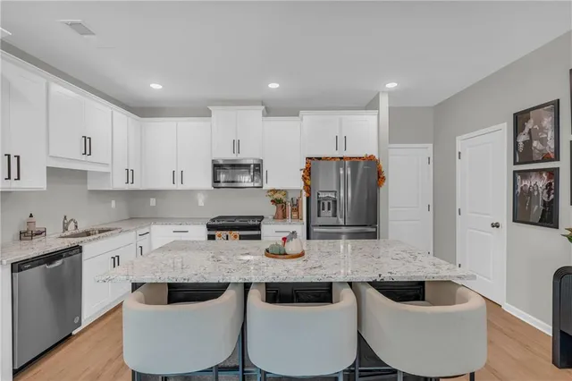 a kitchen with stainless steel appliances granite countertop a sink a stove a kitchen island and chairs