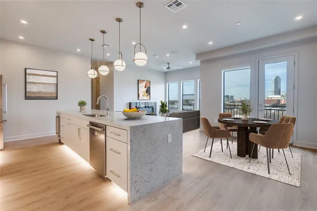 a kitchen with stainless steel appliances granite countertop a stove a sink a kitchen island with chairs and wooden floor