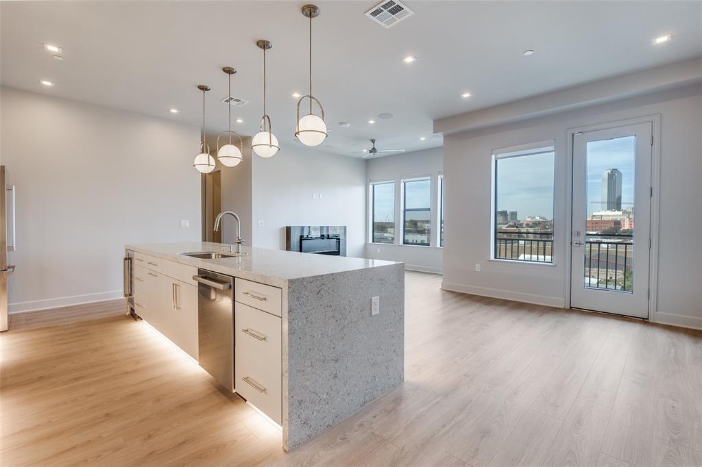 1900 South Ervay Street, Unit 512 Dallas, TX 75215 - Photo 6 of 22 a large kitchen with stainless steel appliances kitchen island a large counter top a sink and a wooden floors