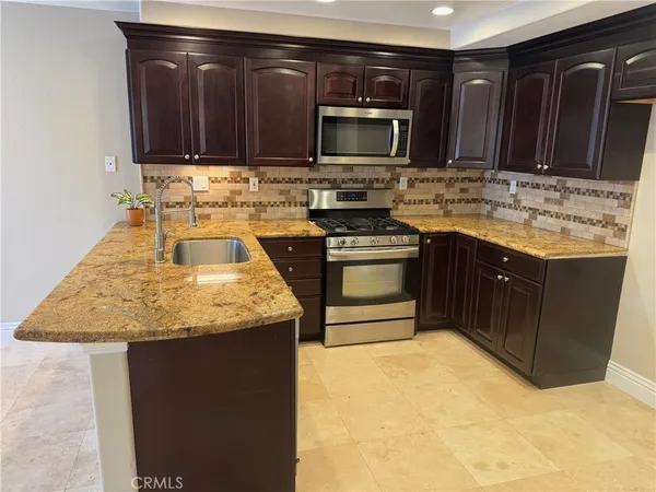 a kitchen with granite countertop a stove sink and microwave