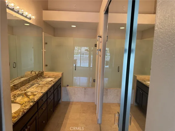 a bathroom with a granite countertop sink a mirror and a shower