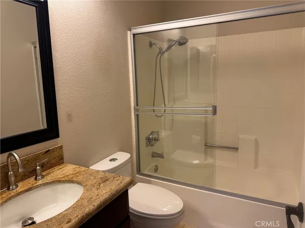 a bathroom with a granite countertop sink toilet and shower