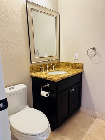 a bathroom with a granite countertop toilet sink and mirror