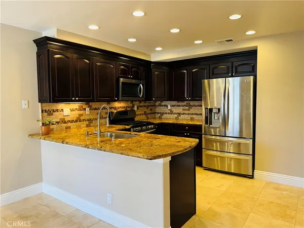 a kitchen with stainless steel appliances granite countertop a refrigerator and a sink