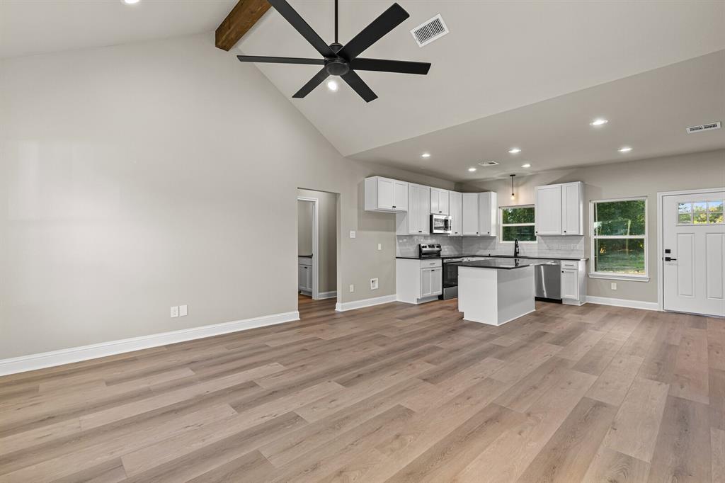 2913 Mildred Street Waco, TX 76706 - Photo 32 of 33 Kitchen featuring dark countertops, open floor plan, beamed ceiling, recessed lighting, and white cabinetry